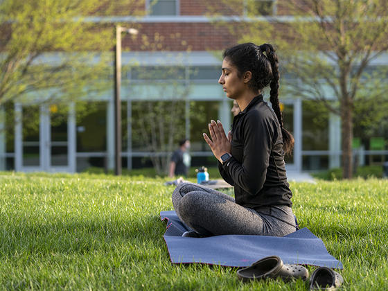 A female student practices yoga outside near the hydroponic greenhouse at the Fairfax Campus