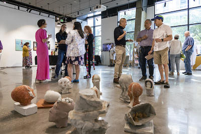 Steven Luu (center) with his piece Fourteenth Heads. Photo by Cristian Torres/Office of University Branding.