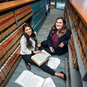 Law students Emily Ahdieh and Samanta Martinez-Villarreal sit on the floor of the library studying in preparation to defend their client.