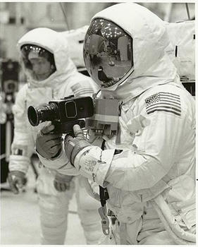 Neil Armstrong and Buzz Aldrin dressed as astronauts and holding a camera. 